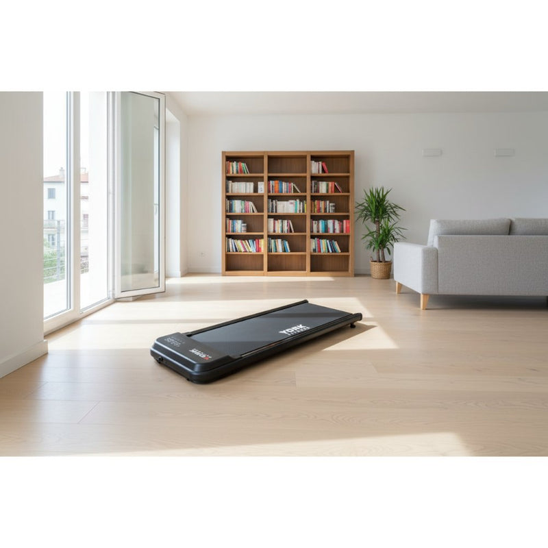 Compact black treadmill in a modern living room with a cozy couch and bookshelf